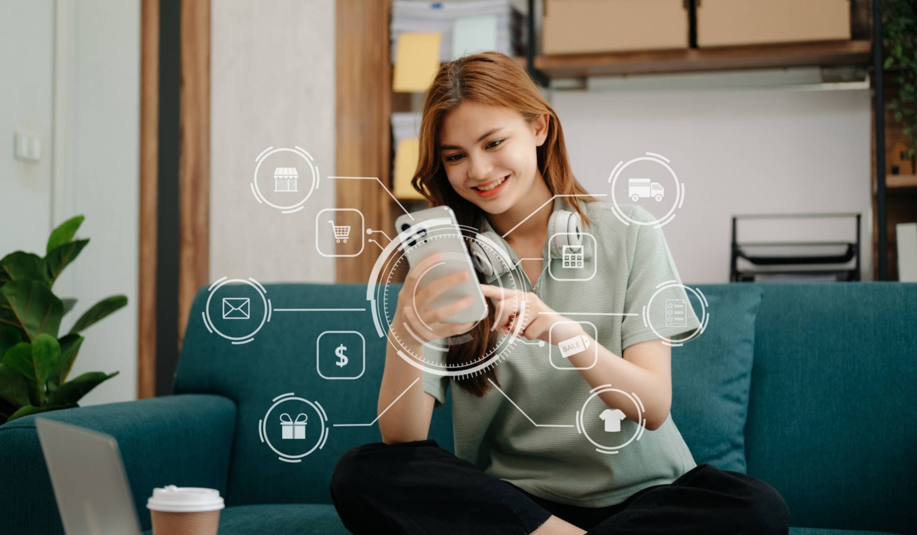 Junge Frau nutzt Shopping-App mit digitalen Symbolen im Wohnzimmer